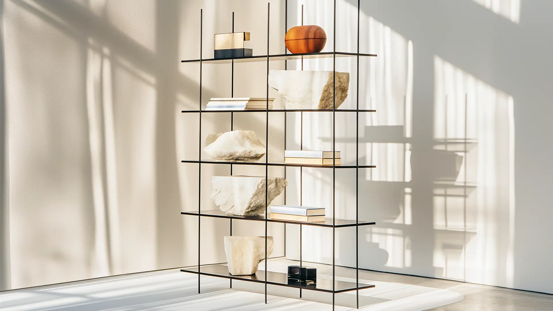 Minimalistisk reol med bøger og sten i et lyst rum.